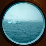 antarktis-reisen-bullauge-eisberg